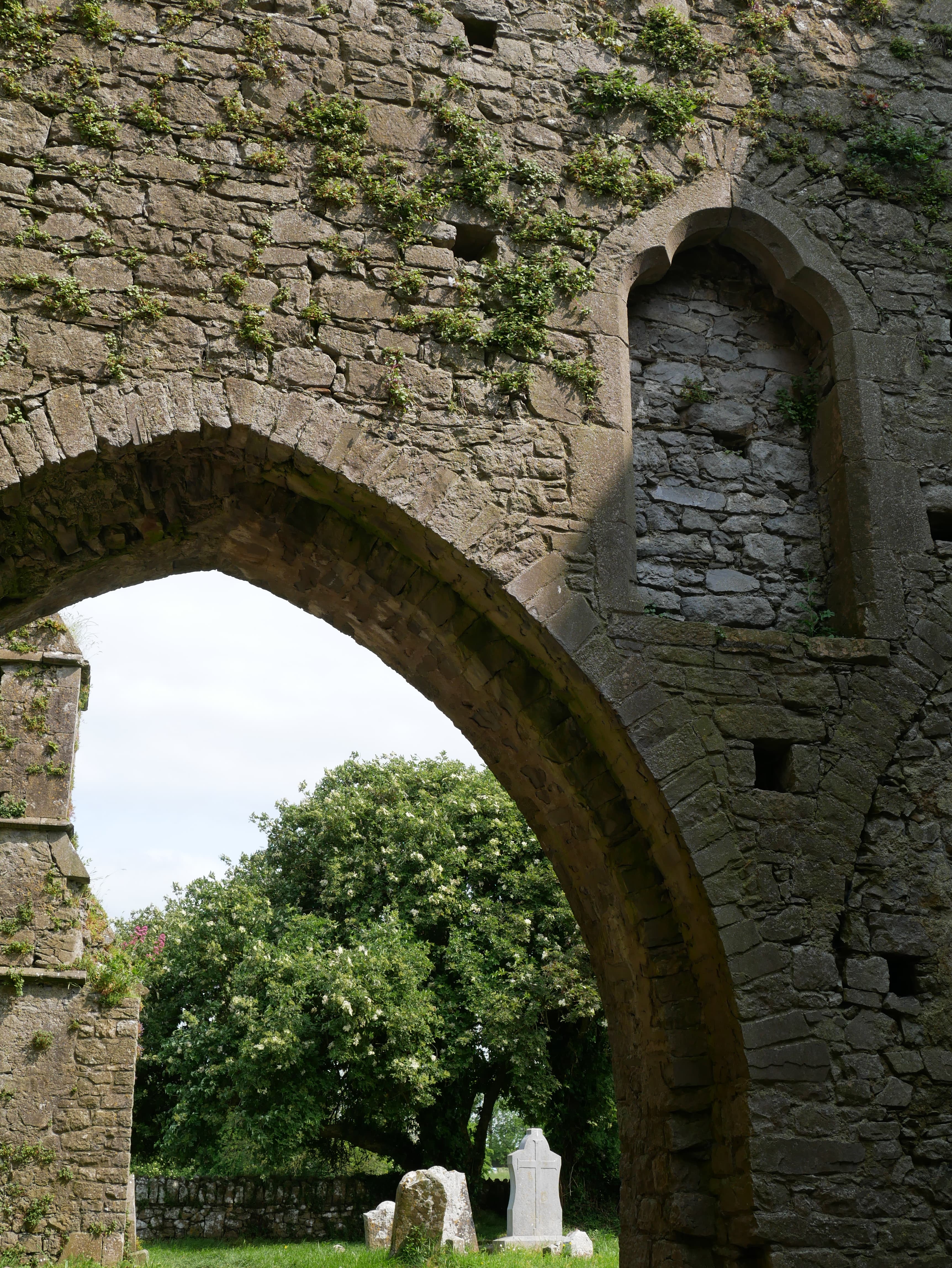 Tall arched windows in the walls of a ruined stone building